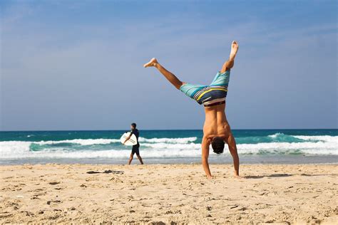 fitness man doing handstand at the beach