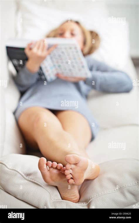 Barefoot Young Woman Lying On Sofa And Reading Book Shallow Depth Of Field Focus On Foot Soles