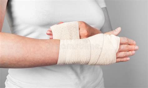 Woman Wrapping Compression Bandage Around Sprained Wrist To Reduce Pain