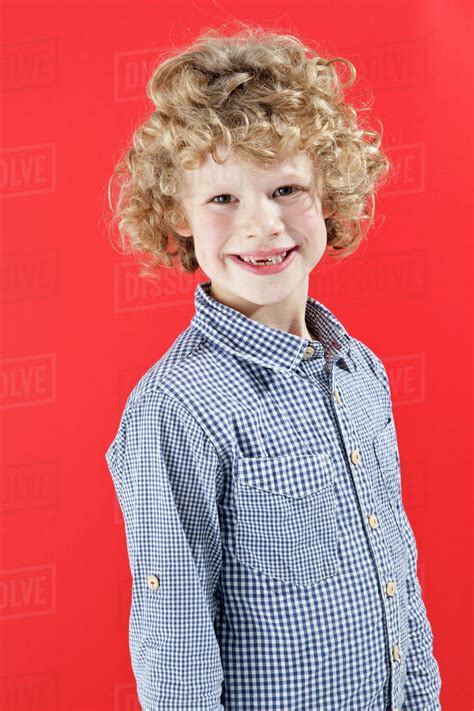 A Boy With Tousled Curly Blond Hair Smiling At The Camera Stock Photo