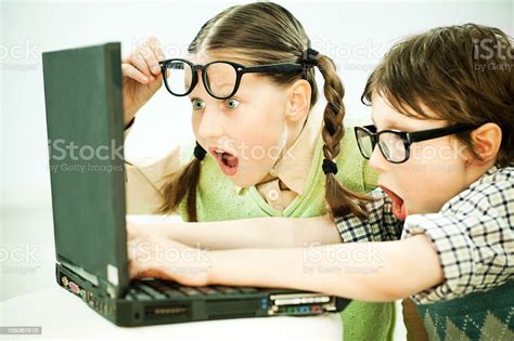 Cute Boy And Girl Nerd Looking At Laptop With Surprise Stock Photo