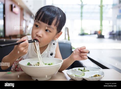 Asian Little Chinese Girl Eating Beef Noodles Soup In Outdoor Cafe