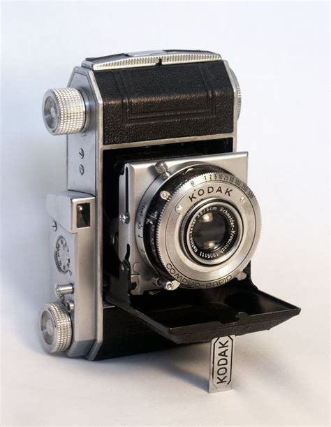 An Old Fashioned Camera Sitting On Top Of A Shelf