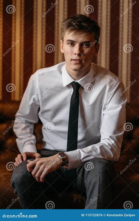 A Young Handsome Man In A Business Suit Is Sitting On The Couch Stock