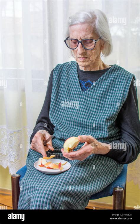 Ninety Years Old Grandma Slicing And Peeling An Apple Indoors Stock