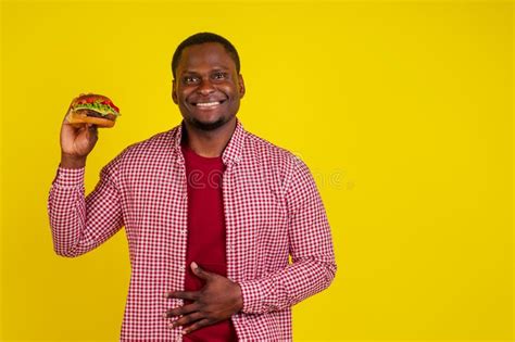 Joven Afroamericano Comiendo Hamburguesa Aislado De Fondo Amarillo