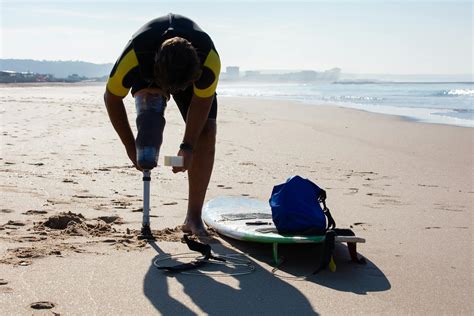 Unrecognizable male surfer amputee wrapping prosthesis with tape on