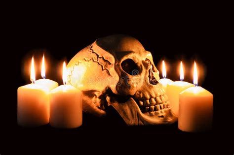 Human Skull In Profile Among Burning Candles In The Dark Scary Still