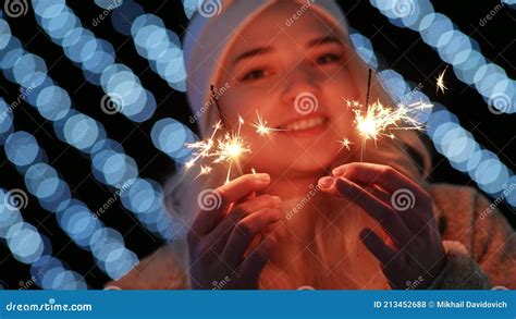 Girl With Sparklers On The Background Of The Christmas Lights Of The