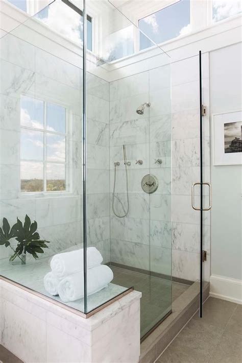 a stunning seamless glass shower is fitted with a marble bench fixed facing a polished nickel