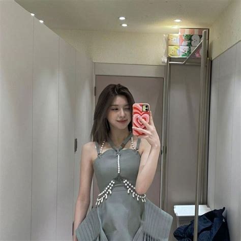 A Woman Taking A Selfie In A Mirror Wearing A Gray Dress And Holding A