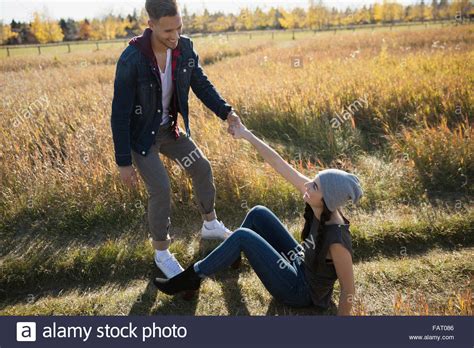Boyfriend Helping Girlfriend Up In Field Stock Photo Alamy