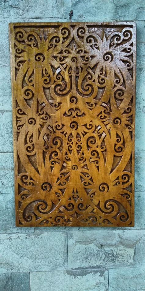 An Intricately Carved Wooden Panel Hanging On The Wall In Front Of A