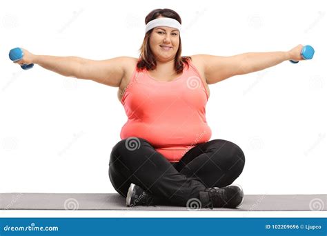 Overweight Woman Seated On An Exercise Mat Exercising With Small Stock