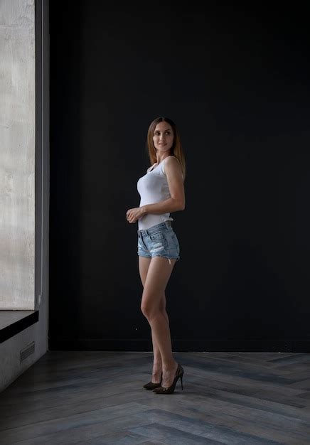 Premium Photo Young Woman In A White Tank Top And Denim Shorts On A