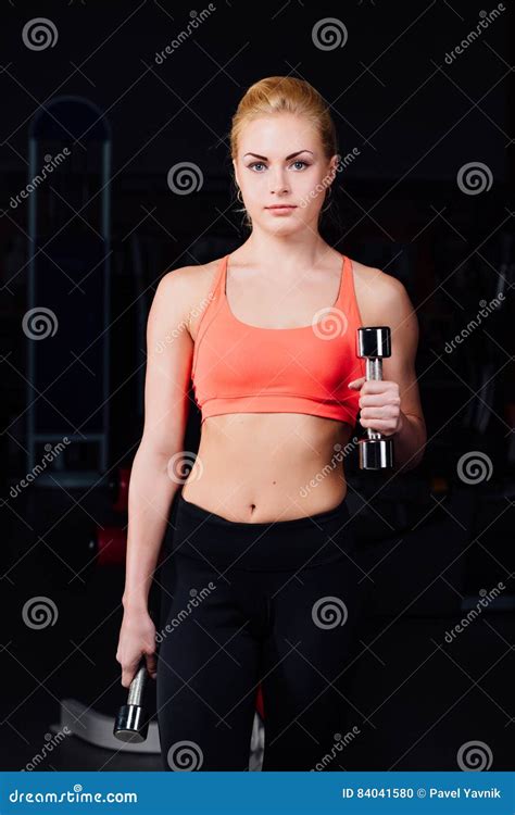 girl doing exercises in her arms biceps and triceps fitness with dumbbells in the gym stock