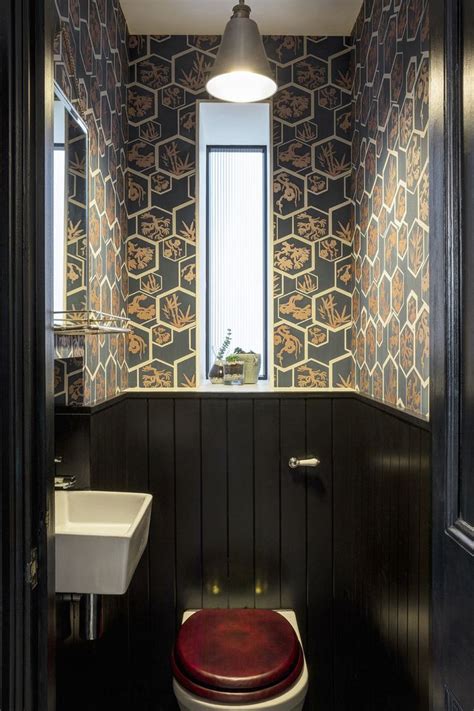Bold wallpaper and dark painted panelling add drama to a tiny