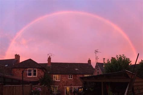 A Double Rainbow In The Sky Over Some Houses