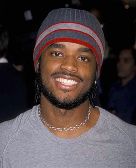 A Man With A Beard Wearing A Gray Shirt And A Red And Grey Striped Beanie