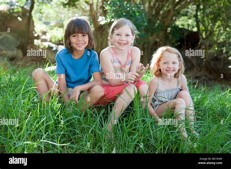 Three Children Sitting On Grass Stock Photo Alamy