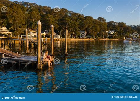 Two Young Women Sitting On The End Of A Pier Stock Photo Image Of
