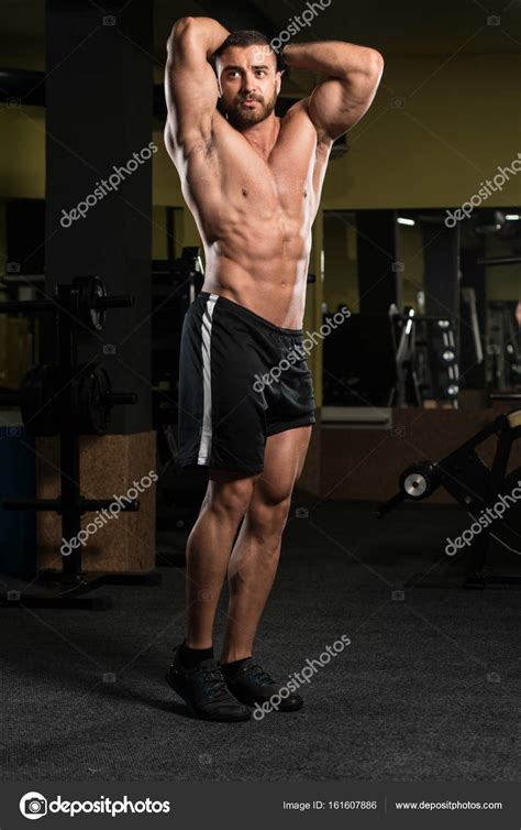 Handsome Muscular Man Flexing Muscles In Gym — Stock Photo © Ibrak