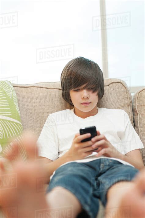 Teenage Boy Sitting On Sofa Using Smartphone Stock Photo Dissolve