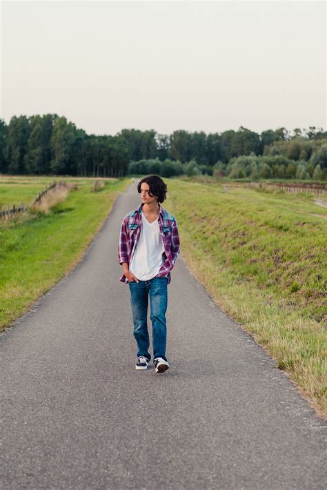 Teenage Boy Walking On A Long Road In The Fields By Stocksy