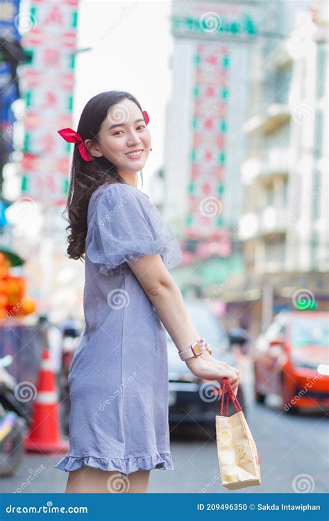 asian beautiful girl in chinese dress is smiling and walking on street in china town stock