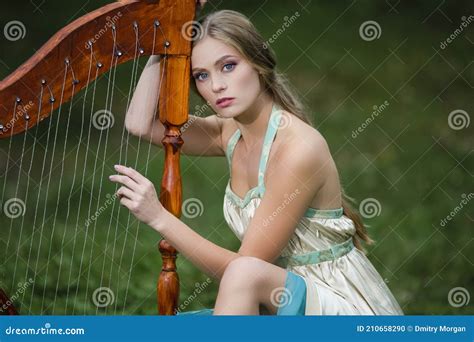 Relaxing Female Harpist Woman In Light Dress Playing The Harp In Park