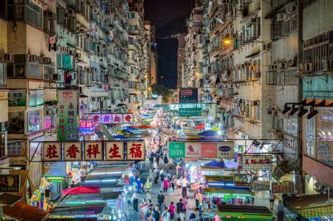 A Crowded City Street At Night With Lots Of Signs And People Walking