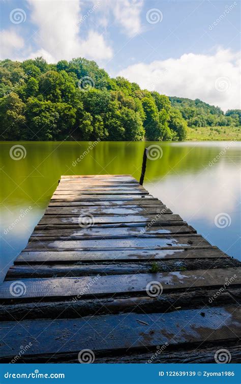 Wooden Pier Or Jetty And A Boat On Lake Sunset And Sky Reflection Water