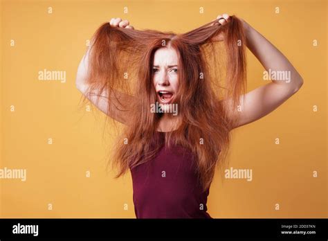 Frustrated Young Woman Pulling And Tearing Her Long Red Hair On A Bad