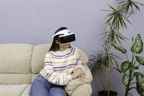 Creative Teen Girl In Virtual Reality Glasses Sitting On A Couch In Her