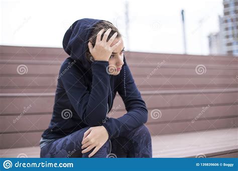 Worried Sad And Depressing Young Woman Sits Outside Stock Photo