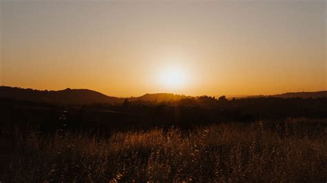 Download Wallpaper 1366x768 Sunset The Sun Rays Vast Hills Tablet