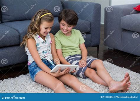 Siblings Using Digital Tablet In Living Room Stock Photo Image Of