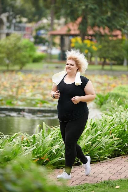 Premium Photo Smiling Curvy Young Woman Jogging In Park On Sunny Day