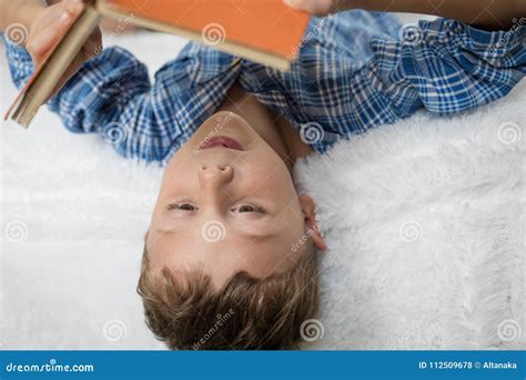 Little Boy Is Lying On The Bed And Reading A Book Stock Photo Image