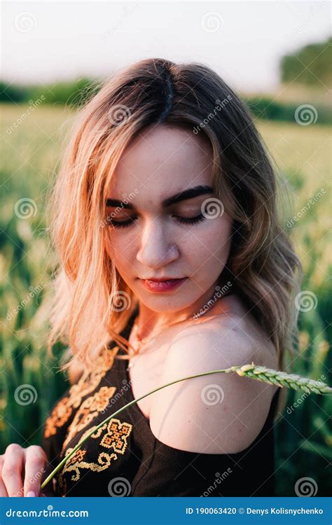 Young Slender Girl Embroidered Dress In A Large Wheat Field At Sunset