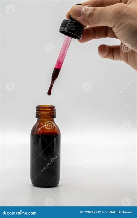 Hand Holding The Dropper With Red Color Over The Amber Glass Bo Stock