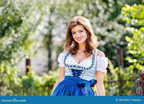 Beautiful Young Woman In Traditional Bavarian Dress In Park Stock Photo