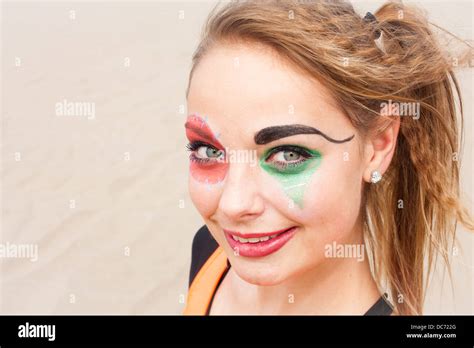 A Close Up Head Shot Of A Young Female Circus Performer With Clown Make Up Smiling And Looking