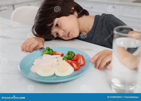 Cute Little Boy Refusing To Eat Dinner In Kitchen Stock Photo Image