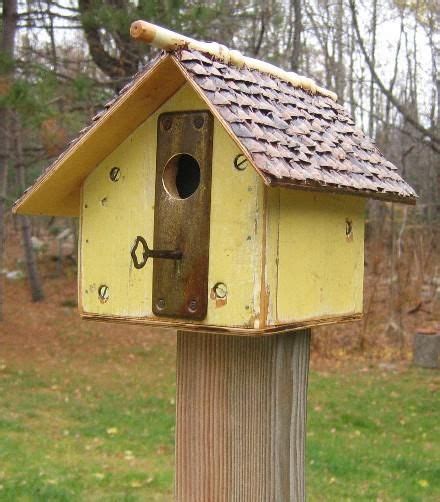 A Yellow Bird House On Top Of A Wooden Post