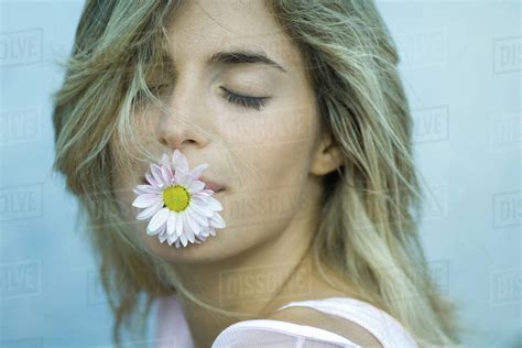 Woman Holding Flower In Mouth Eyes Closed Close Up Stock Photo