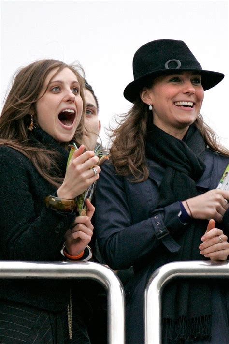 Two Women Are Laughing While Standing Next To Each Other In The Stands At A Sporting Event