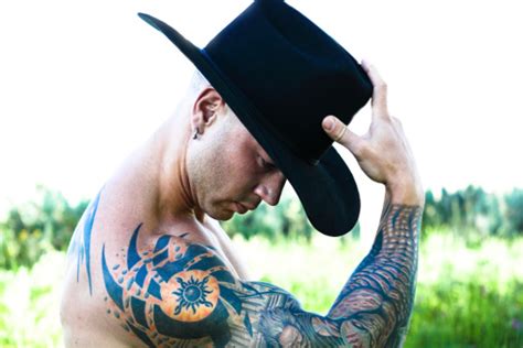 Cowboy With Tattoo Wearing Black Stetson In Camp Butch Pose Stock Photo