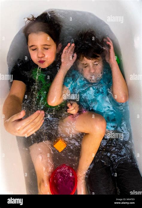 Twin Caucasian Brothers Play In Their Water Filled Bathtub Together With Their Clothes On Stock