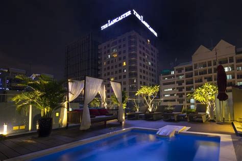 An Outdoor Swimming Pool At Night With Buildings In The Background